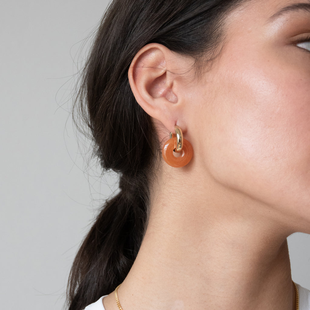 round orange gemstone pendants on gold round hoop earrings 