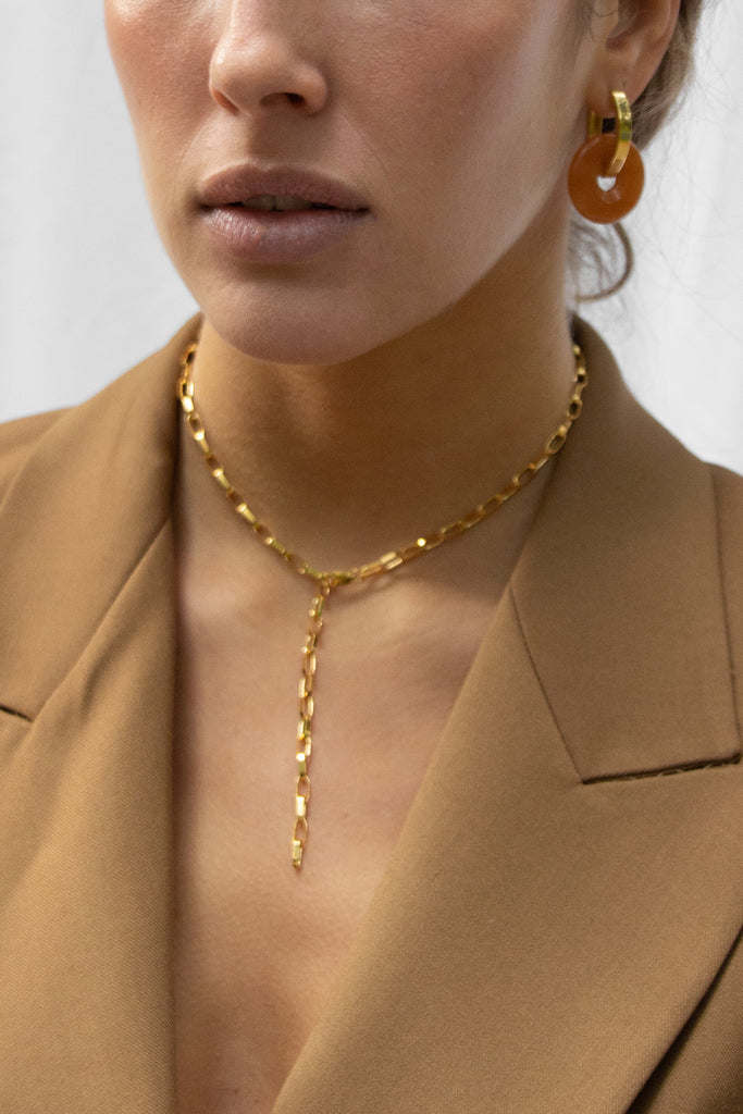 golden y-chain from sustainable jewelry company LLR Studios paired with oval shaped hoops and orange aventurine pendants
